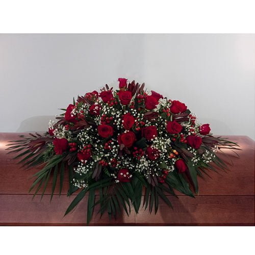 Coussin de cercueil composé de roses rouges et d’hypericum