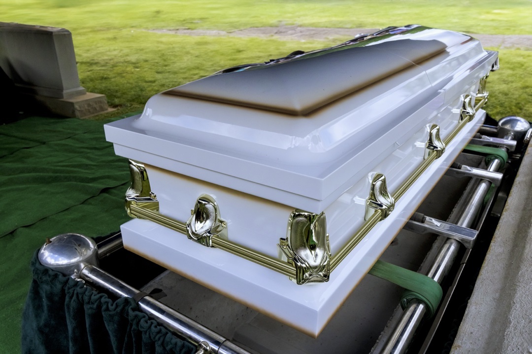 Image d'un cercueil blanc pret à être en terre.